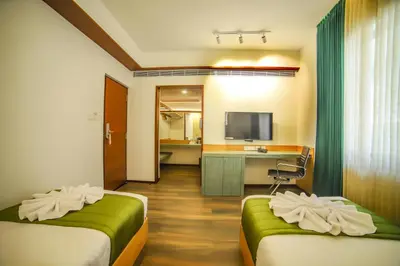a hotel room with two beds and a desk at Hotel Villa Maryam in Kozhikode