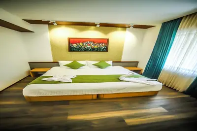a bedroom with a large bed with a painting on the wall at Hotel Villa Maryam in Kozhikode