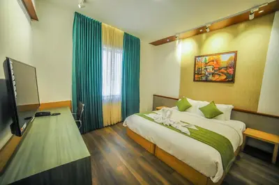 a bedroom with a bed and a flat screen tv at Hotel Villa Maryam in Kozhikode