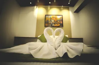 two white swans are sitting on a bed at Hotel Villa Maryam in Kozhikode