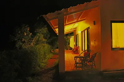 a couple of chairs sitting on a porch at night at The Tamarillo in Ooty