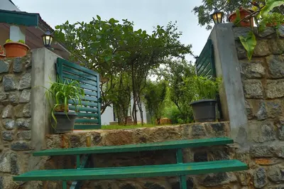 a green bench against a stone wall with potted plants at The Tamarillo in Ooty