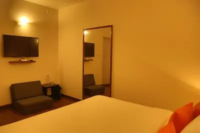 a bedroom with a mirror and a bed and a chair at The Tamarillo in Ooty