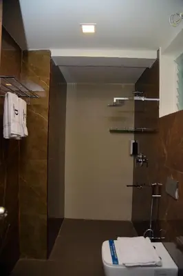 a bathroom with a toilet and a glass shower at D Wayfarer Inn Resort in Erode