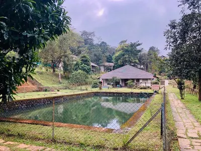 a pond in a park with a house in the background at Abad Brookside Wayanad in Vythiri