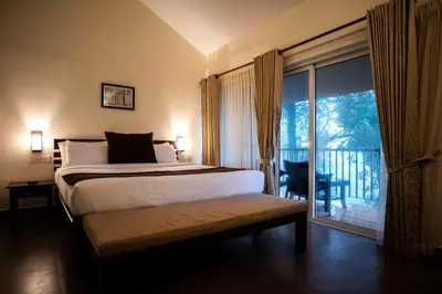 a bedroom with a bed and a window with a balcony at Abad Brookside Wayanad in Vythiri
