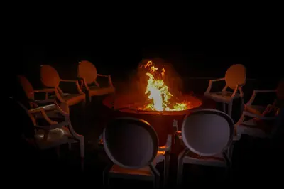 a table with a fire in the middle of a group of chairs at La Montana by TGI in Ooty