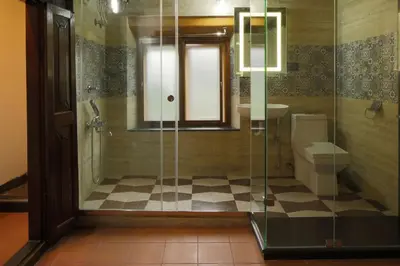 a bathroom with a glass shower and a toilet at Kunnampath Heritage Nalukettu in Trichūr
