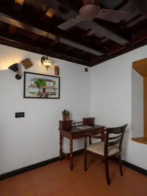 a table and a chair in a room with a ceiling at Kunnampath Heritage Nalukettu in Trichūr
