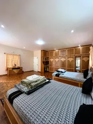 two beds in a large room with wooden cabinets at Chill Inn - Families Only in Ooty