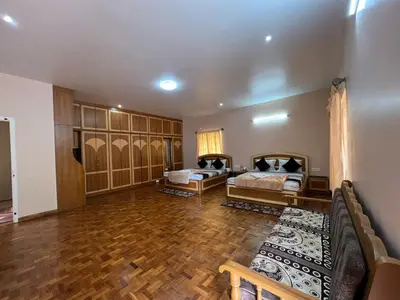 a living room with two beds and a wooden floor at Chill Inn - Families Only in Ooty