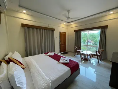 a hotel room with a bed and a table with chairs at Le Eden Premium Wayanad Pool Resort in Sultan Bathery