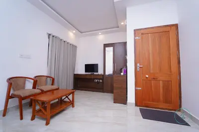 a living room with a wooden door and a table and chairs at Le Eden Premium Wayanad Pool Resort in Sultan Bathery