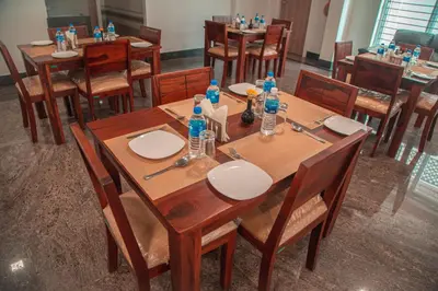 a dining room with wooden tables and chairs with water bottles on them at Park Avenue Suites in Coimbatore