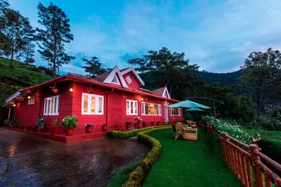 a red house with a fence in front of it at Teanest by Nature Resorts and Stays in Coonoor