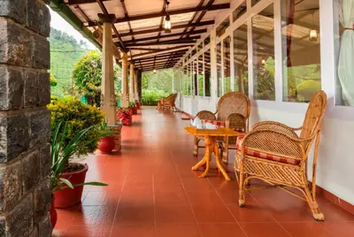 a porch with chairs and tables and a table at Teanest by Nature Resorts and Stays in Coonoor