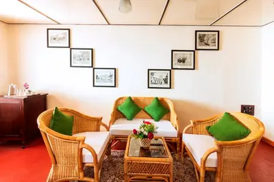 a room with wicker chairs and a table with green pillows at Teanest by Nature Resorts and Stays in Coonoor