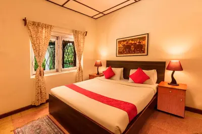 a bedroom with a large bed with red pillows at Teanest by Nature Resorts and Stays in Coonoor