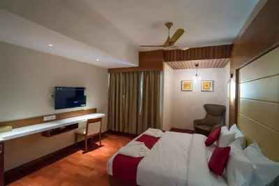 a hotel room with a bed and a desk and a television at JK HOTELS in Coimbatore