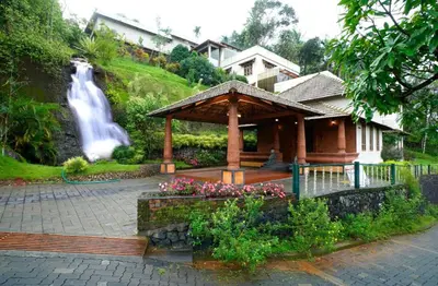 a house with a gazebo next to a waterfall at Indeevara Luxury Resort and Spa, Wayanad in Vythiri