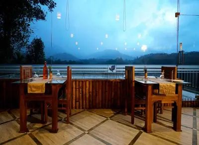 two tables and chairs with a view of a lake at Indeevara Luxury Resort and Spa, Wayanad in Vythiri