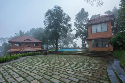 a house with a stone driveway next to a building at Indeevara Luxury Resort and Spa, Wayanad in Vythiri