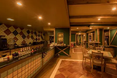 a restaurant with a bar and a table and chairs at Hotel Nahar Nilgiris in Ooty