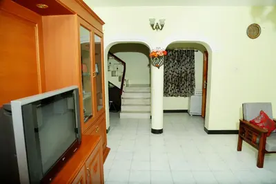 a living room with a tv and a hallway at ZuriEL Suite GUEST HOUSE in Coimbatore
