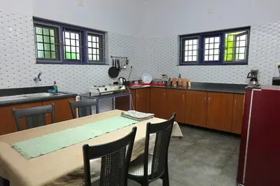 a kitchen with a wooden table and a table and chairs at Monsoon Apartments in Kannur