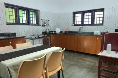 a kitchen with a bed and chairs in a room at Monsoon Apartments in Kannur