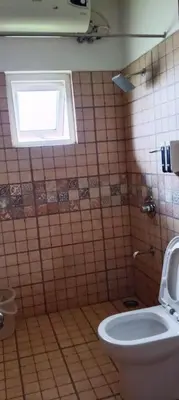 a bathroom with a toilet and a window at The Realm in Coonoor