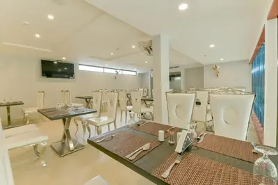 a dining room with white chairs and a table at Super Townhouse Edassery Blue Bells in Cochin