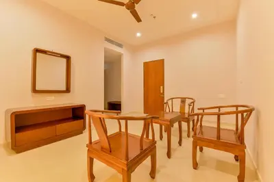 a dining room with a table and chairs and a mirror at Super Townhouse Edassery Blue Bells in Cochin