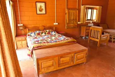 a bedroom with a bed and a table and a chair at Kabbe Holidays in Madikeri