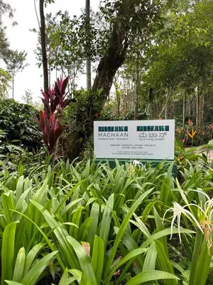 a sign in the middle of a garden with plants at Machaan Wilderness Lodge Nagarahole in Srimangala