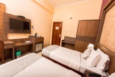a hotel room with two beds and a flat screen tv at Kallada Golden Hotel in Trichūr