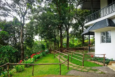 a garden next to a house with red tulips at Golden Fern Resort in Kanthalloor