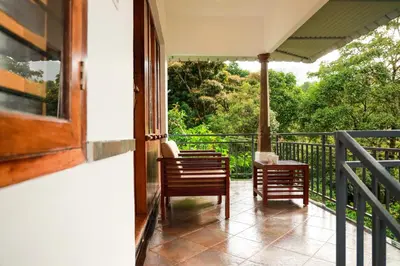 a balcony with two chairs and a table at Golden Fern Resort in Kanthalloor