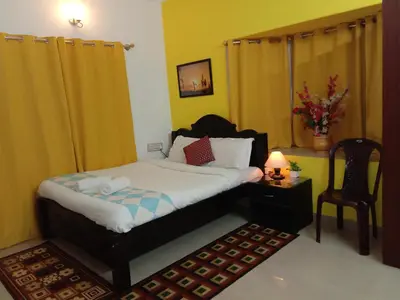a bedroom with a bed and a table and a chair at Coorg Homeland Homestay -With Kitchenette in Madikeri
