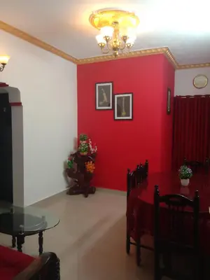 a living room with a red wall and a table at Coorg Homeland Homestay -With Kitchenette in Madikeri