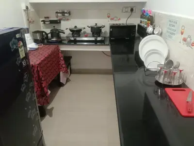 a kitchen with a black counter top and a table at Coorg Homeland Homestay -With Kitchenette in Madikeri