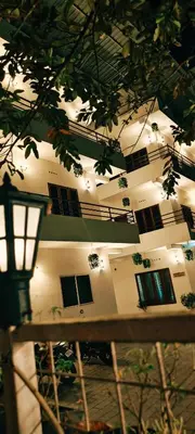 a building with windows and a tree in the foreground at Oxxon Airport Hotel in Angamali