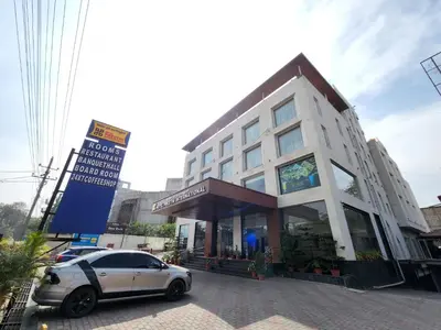 a white car parked in front of a building at Hotel Preethi International in Mysore
