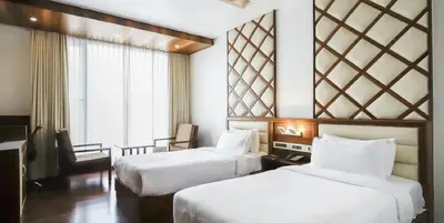 a hotel room with two beds and a window at Hotel Preethi International in Mysore