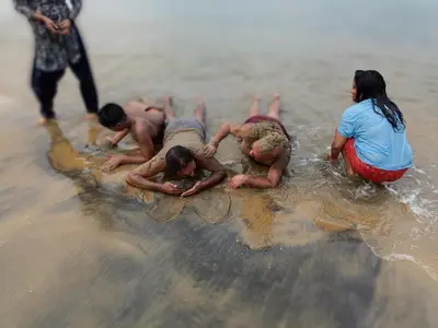 a group of people playing in the water on the beach at Swasthigriha's Beach Homestay, Cherai in Cherai Beach