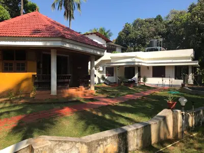 a white house with a red roof and a yard at Ayuryogashram Heritage in Trichūr
