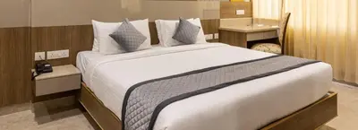 a bedroom with a large bed with white sheets and pillows at Rathna Residency in Erode