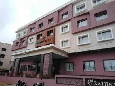 a pink and white building with motorcycles parked in front of it at Rathna Residency in Erode