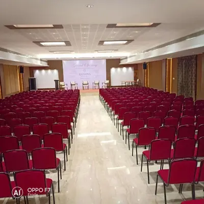 a lecture hall with red chairs and a projection screen at Rathna Residency in Erode