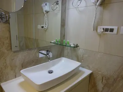 a bathroom with a white sink and a mirror at Paramount Tower in Kozhikode
